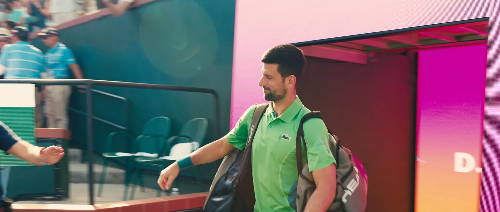 Tennis pro walking backstage past a magenta wall