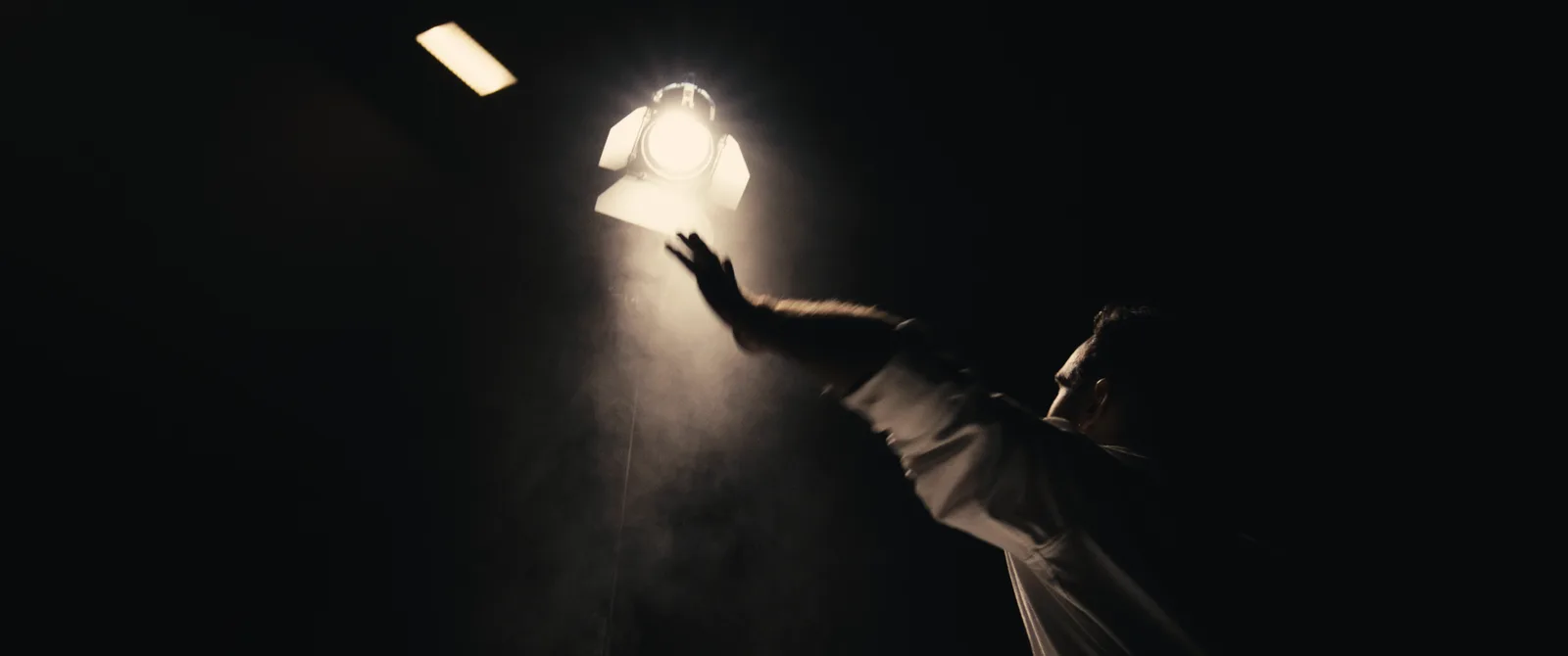 Hand reaching toward a film light through haze