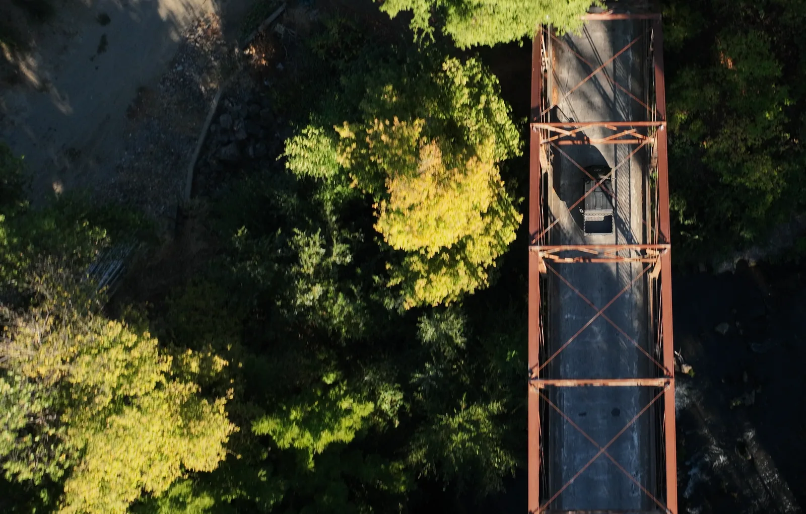 Top-down aerial of a truck crossing a forest bridge