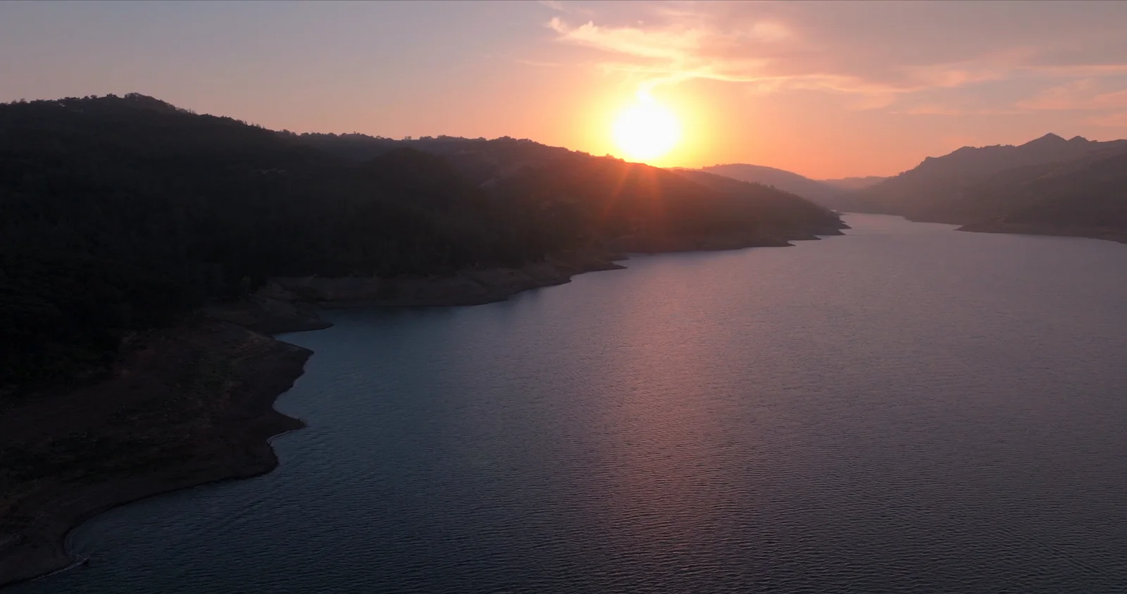 Aerial sunset over a lake in the Northern California hills
